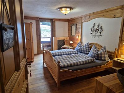 Ein gemütliches Zimmer mit Holzverkleidung und einem großen Doppelbett. Es gibt Fenster mit Blick nach draußen und einen modernen Kleiderschrank.