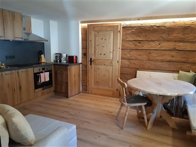 Útulná kuchyně s dřevěnými prvky a moderním designem. Kulatý stůl a světlé prostředí vytvářejí přívětivou atmosféru.