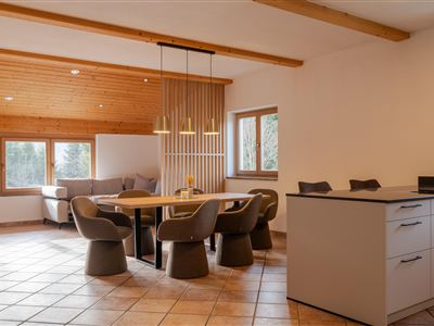 Een moderne eetkamer met een ronde tafel en stoelen. Grote ramen zorgen voor veel licht en een gezellige sfeer.