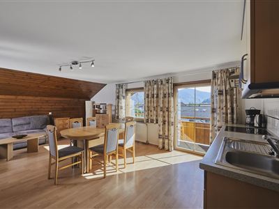 A cozy interior with a seating area and a dining table. Large windows provide plenty of daylight and offer a view of the surroundings.