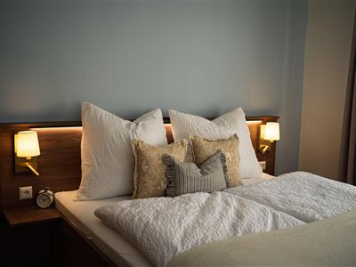 Een moderne slaapkamer met een groot bed en zachte kussens. Zachte verlichting zorgt voor een gezellige sfeer.