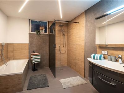 A modern bathroom with a freestanding bathtub and a separate shower. It is in neutral colors and features modern fixtures.