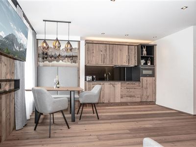 Een moderne keuken met houten panelen en een eetgedeelte. Grote ramen zorgen voor veel licht in de stijlvolle ruimte.