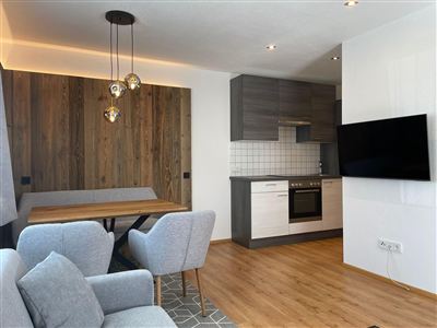 Eine moderne Wohnküche mit einem Holzdekor und einer eleganten Küchenzeile. Das Zimmer ist hell und einladend mit einem gemütlichen Essbereich.