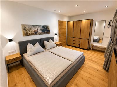 Gezellige slaapkamer met comfortabel tweepersoonsbed, ruime kast, televisie, natuurlijke houten elementen en stijlvolle inrichting.