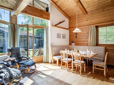 Eine gemütliche Wohnung mit Holzdekor und viel natürlichem Licht. Im Vordergrund steht ein Esstisch mit Äpfeln, und im Hintergrund sieht man eine Küche.