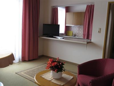 A cozy living room with a dining table and a television. The warm colors and the creative flower table create an inviting atmosphere.