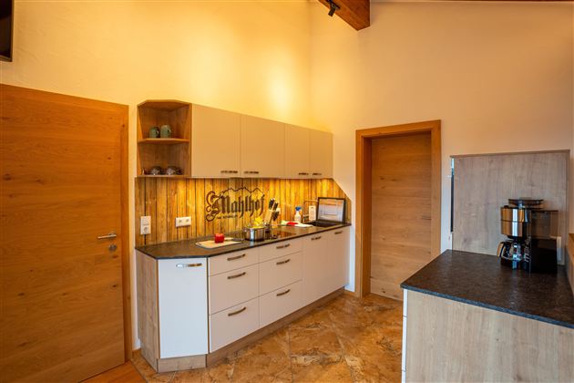 A modern kitchen with bright furniture and wooden details. The room is well-lit and friendly designed.