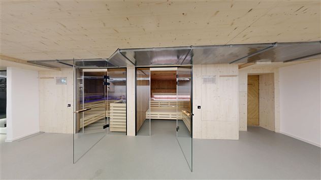 A modern wellness area with glass walls and wooden interior. The room includes two saunas and a relaxing atmosphere.