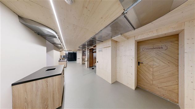 A modern interior with wooden paneling and a clear, minimalist design. On the right side, there is a door with the label "Sauna area".