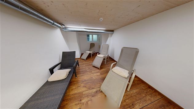 A quiet room with loungers and a light wooden floor. The walls are simple and tidy, ideal for relaxing.