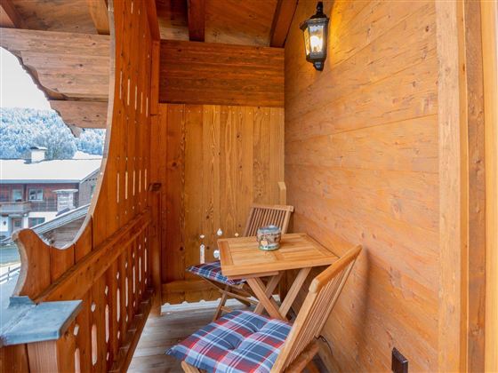 A cozy balcony with wooden furniture and a lantern. The wooden paneling creates a warm and inviting atmosphere.