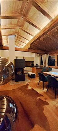 A modern living room with a wooden ceiling and elegant furniture. The room is brightly lit and conveys a cozy atmosphere.