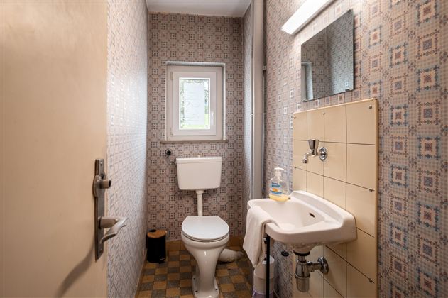 A small bathroom with a toilet and a sink. The walls are decorated with patterned wallpaper.