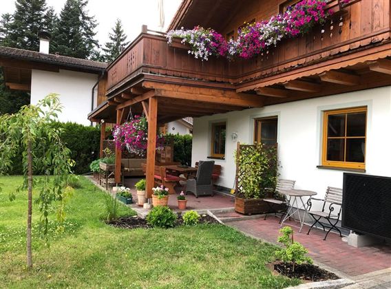 Een gezellig huis met een mooi balkon, dat versierd is met kleurrijke bloemen. De tuin biedt een uitnodigende zitplek en een groen gazon.