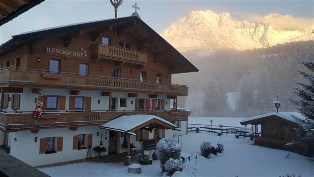 Ein schönes Chalet im Winter, umgeben von Schnee und Bergen. Die Fassade des Hauses ist aus Holz und die Atmosphäre ist ruhig und malerisch.