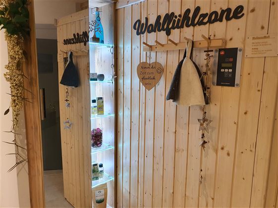 Ein einladender Bereich mit holzverkleideten Wänden. Es gibt Regale mit Pflegeprodukten und dekorative Elemente für eine Wohlfühlatmosphäre.