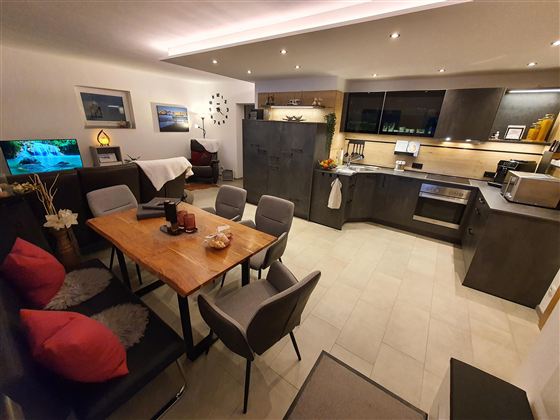 Eine moderne Küche mit einem Essbereich und komfortablen Stühlen. Der Raum ist freundlich und gut beleuchtet, ideal für geselliges Beisammensein.