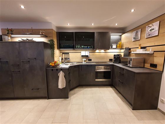 Eine moderne Küche mit dunklen Schränken und Holzdetails. Sie ist gut ausgestattet mit Geräten und hat eine helle, einladende Atmosphäre.