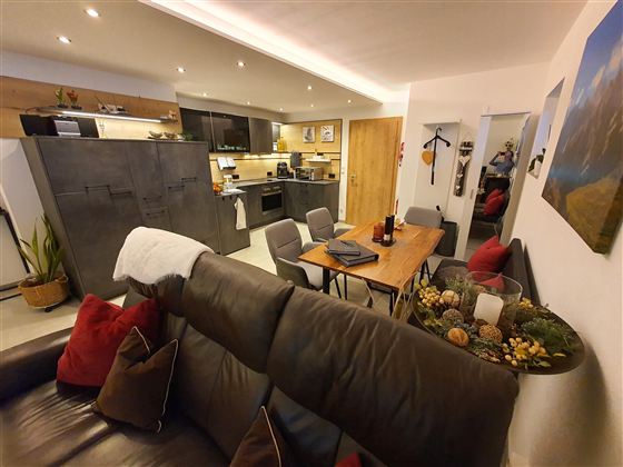 Eine moderne und gemütliche Wohnküche mit einem Esstisch und Stühlen. Der Raum ist hell erleuchtet und gemütlich eingerichtet.