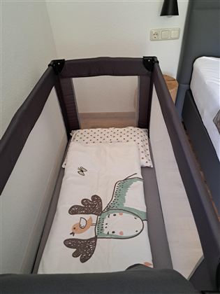 Een ledikant met een kleurrijke dekbed en een matras. De ruimte lijkt helder en modern.