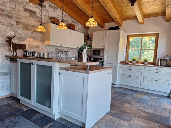 Een moderne keuken met houten plafonds en stenen muren. De ruimte is helder en uitnodigend met veel opbergruimte en stijlvolle details.