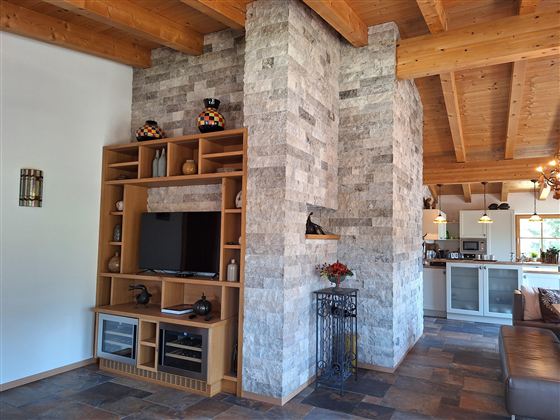 Een stijlvolle woonkamer met een moderne stenen muur en een tv-meubel. De open ruimte heeft houten balken en een uitnodigende sfeer.