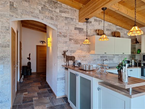 Een moderne keuken met houten elementen en een gezellige sfeer. De muren zijn bekleed met steen, en zachte verlichting zorgt voor uitnodigend licht.