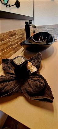 Een moderne wastafel met een elegant ontwerp en een decoratieve handdoek. De kleuren zijn stijlvol en passen goed bij de badkameromgeving.