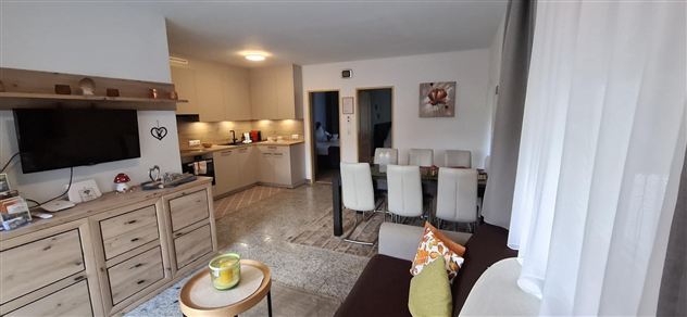 A modern apartment with an open living and dining area. The kitchenette and dining table are well furnished and create an inviting atmosphere.