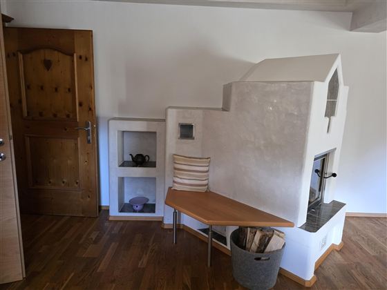 Een gezellige woonkamer met een moderne open haard en een houten rek. De muren zijn licht en de vloer is van hout.