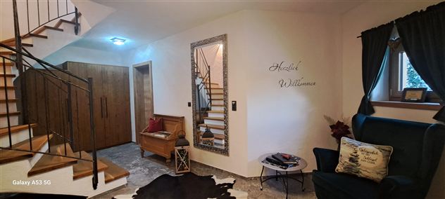 Ein einladender Eingangsbereich mit einer Treppe und einem gemütlichen Sessel. An der Wand steht der Schriftzug "Herzlich Willkommen".