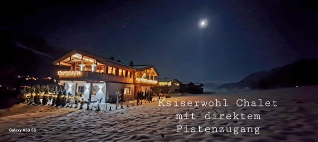 Ein gemütliches Chalet im Winter, umgeben von Schnee und beleuchtet von einem klaren Mond. Das Chalet bietet direkten Zugang zu den Pisten.