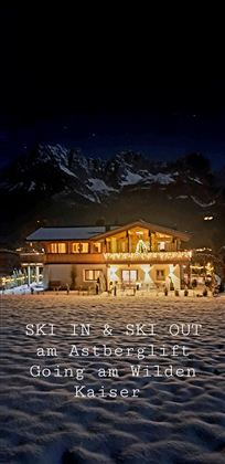 Eine gemütliche Berghütte im Schnee mit festlicher Beleuchtung. Im Hintergrund sind beeindruckende Berge zu sehen.