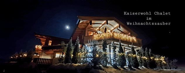 Ein wunderschönes Chalet, festlich mit Lichtern dekoriert, unter einem klaren Nachthimmel. Der Mond leuchtet über dem Kaiserwohl Chalet im Weihnachtszauber.