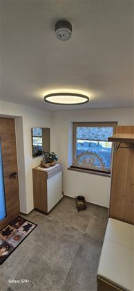 Ein heller Flur mit modernen Möbeln und einem großen Fenster. Die Wände sind hell gestrichen und es gibt eine angenehme Atmosphäre.