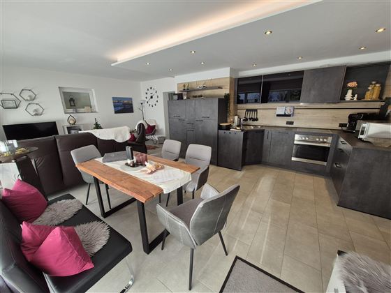 Eine moderne Wohnung mit offener Küche und Essbereich. Der Raum ist hell und geräumig, mit eleganten Möbeln und dekorativen Akzenten.