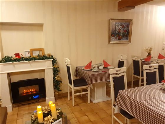 Ein gemütlicher Essbereich mit karierten Tischdecken und weißen Stühlen. Auf dem Tisch stehen Kerzen und eine dekorative Weihnachtsdekoration.