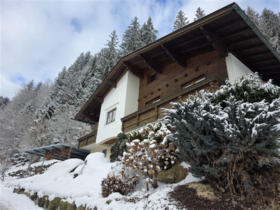 Een prachtig oud huis in een besneeuwd landschap. Op de achtergrond rijzen hoge bomen op.