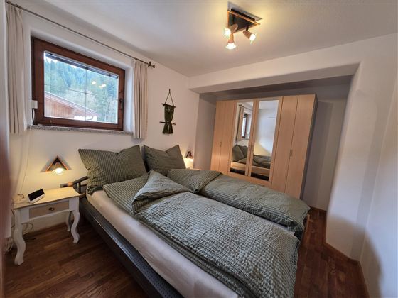 Een gezellige slaapkamer met twee eenpersoonsbedden en een grote kledingkast. De ramen bieden uitzicht op de natuur en de ruimte is licht en uitnodigend.