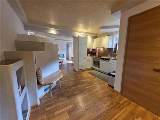 Eine helle, modern eingerichtete Küche mit Holzfußboden. Der Raum hat offene Bereiche und viel Platz für Bewegung.