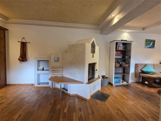 Ein stilvolles Wohnzimmer mit einer modernen Heizung und Holzboden. An der Wand befindet sich ein Regal und gemütliche Sitzmöglichkeiten.