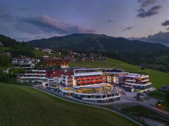 Een modern hotel in een schilderachtig landschap met zachte heuvels. De gebouwen zijn een mix van traditionele en eigentijdse architectuur.
