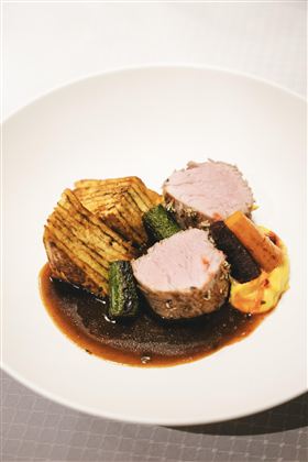 Ein kreativ angerichtetes Gericht mit zartem Fleisch, gebratenem Gemüse und einer dunklen Sauce. Dazu gibt es Kartoffeln in Form von Scheiben.