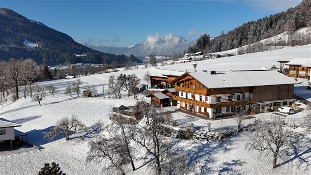 Ein malerisches Chalet im Schnee, umgeben von einer winterlichen Landschaft. Die Berge und der klare Himmel verleihen der Szene eine ruhige Atmosphäre.