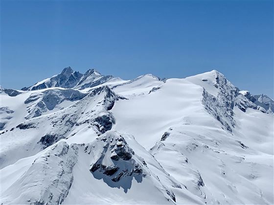 An impressive alpine landscape with snow-covered mountains. The clear blue sky lets the beauty of nature shine.