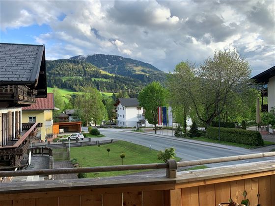 Eine malerische Landschaft mit grünen Hügeln und einer ruhigen Straße. Im Hintergrund sind Berge und Wolken zu sehen.