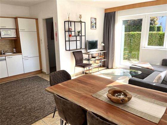 Eine helle, einladende Wohnung mit offener Küche und Essbereich. Der Wohnbereich ist modern und gemütlich mit einer großen Fensterfront.