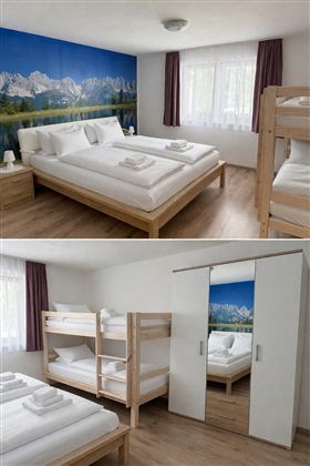 A bright room with two beds and a bunk bed. The wall is decorated with a mountain picture and there are large windows for plenty of daylight.