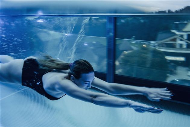 Een vrouw zwemt elegant in een zwembad. Het water is helder en weerspiegelt het licht.